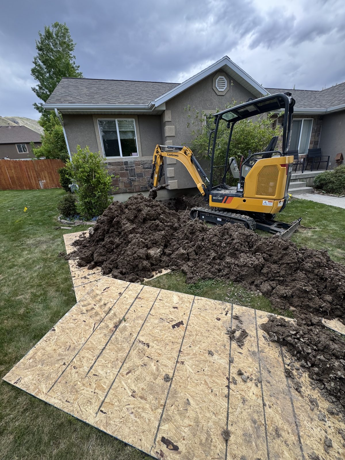 Mini excavator digging a sewer line at a Utah County home